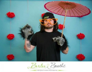 Jarrod with long hair wearing werewolf gloves and orange glasses holding an umbrella